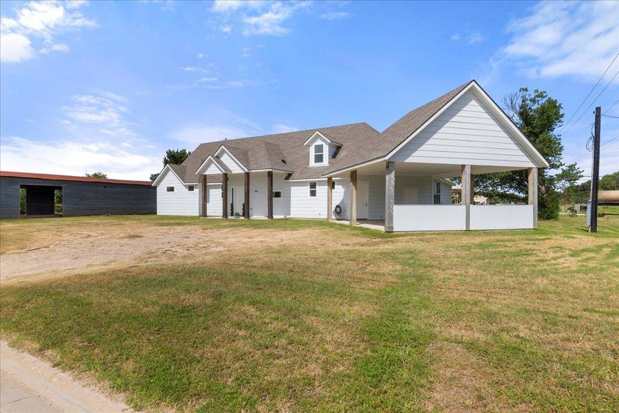 View of front of home featuring a front yard and a shingled roof View of front of home featuring a front yard and a shingled roof
