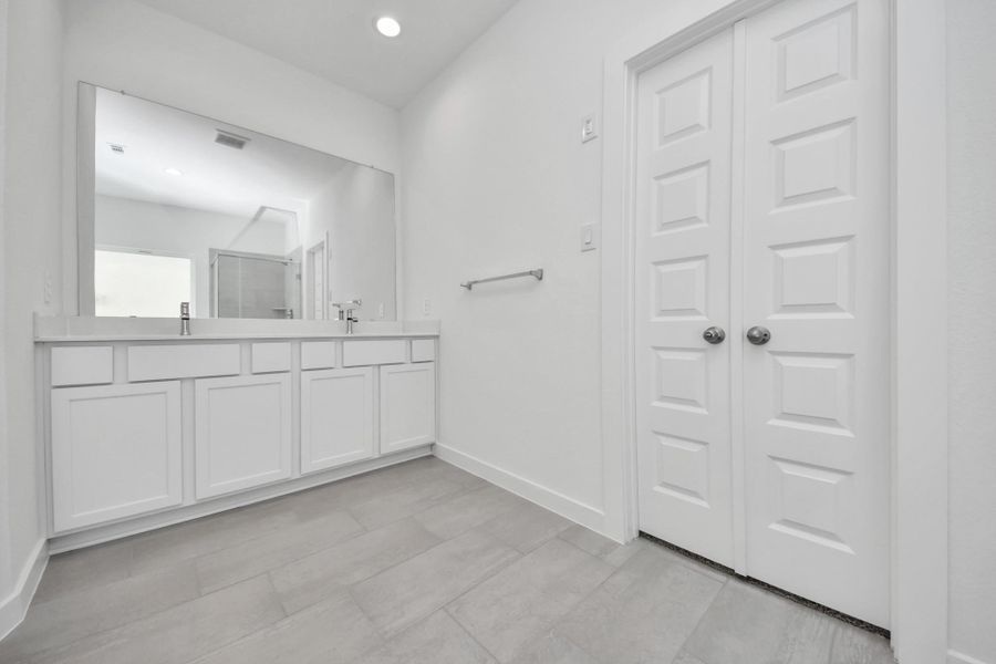Elevate your daily routine at the elegant vanity, now equipped with double sinks, light countertops, modern hardware, and beautiful recessed lights. Sample photo of completed home with similar floor plan. Actual colors and selections may vary.