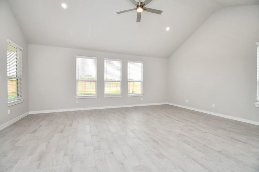 Welcome family and guests to your charming living room! With its high ceilings, recessed lighting, ceiling fan, custom paint, beautiful flooring, and large windows that let in abundant natural light, this room is perfect for gatherings.