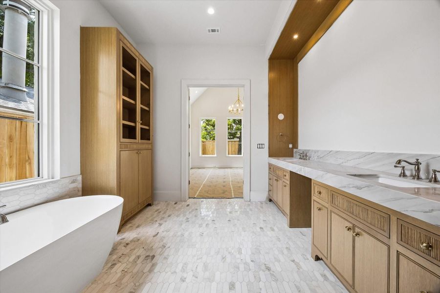 The primary bathroom with white oak vanities, a linen cabinet, quartzite countertops, a freestanding tub, and a separate shower with a built-in bench. Designer-selected fixtures and custom mirrors will complete the space.