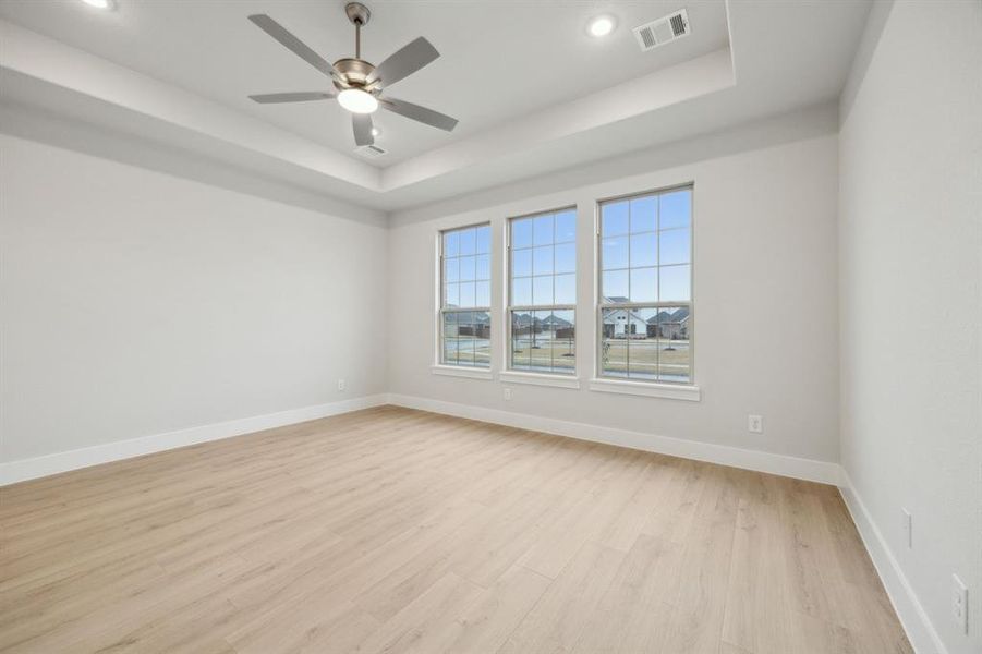 Unfurnished room with ceiling fan, a raised ceiling, and light hardwood / wood-style floors