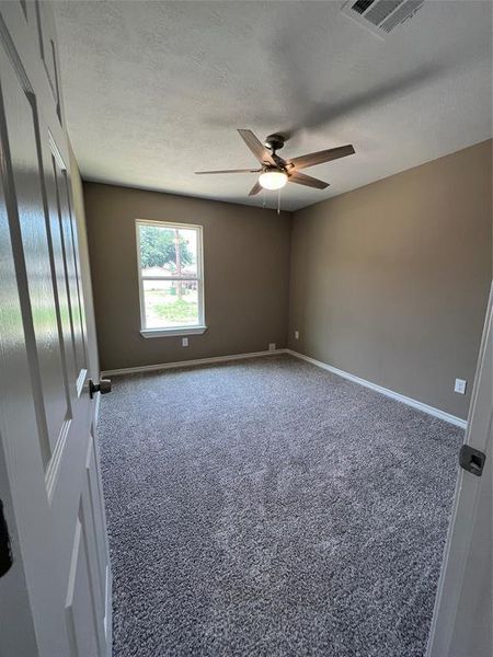Spare room with a textured ceiling, carpet flooring, and ceiling fan