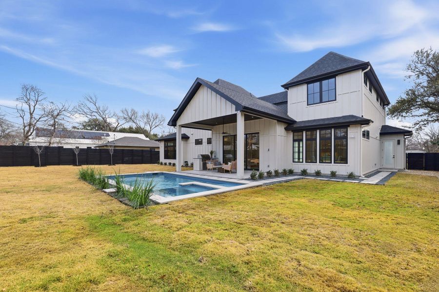 Back of property with board and batten siding, a fenced backyard, roof with shingles, and a patio