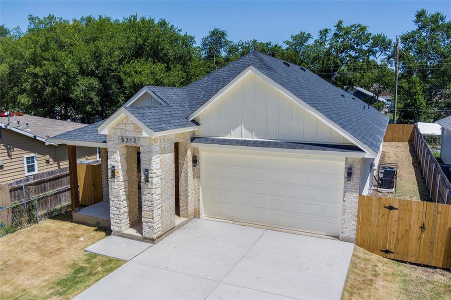 View of front of property featuring a shingled roof, board and batten siding, stone siding, concrete driveway, and a garage
