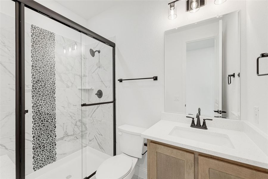 Bathroom with glass-enclosed marble tile shower, wood vanity, white quartz countertop, and black fixtures