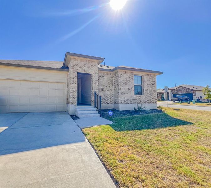 View of front of home featuring driveway, a front lawn, brick siding, and an attached garage