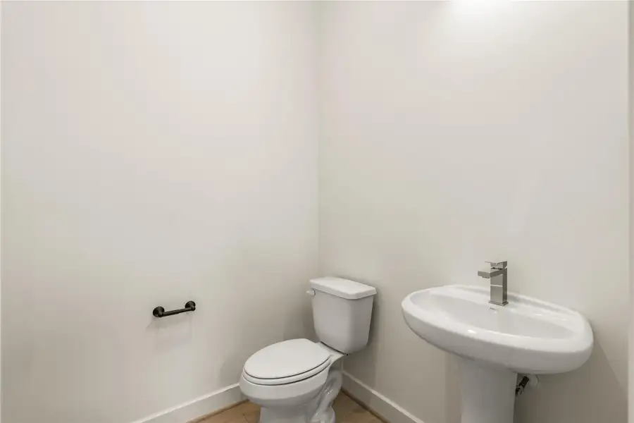 Main-level powder room — clean white pedestal sink, sleek chrome faucet, and matte black hardware.