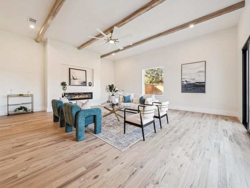 Living room with ceiling fan, beam ceiling, and light wood-type flooring