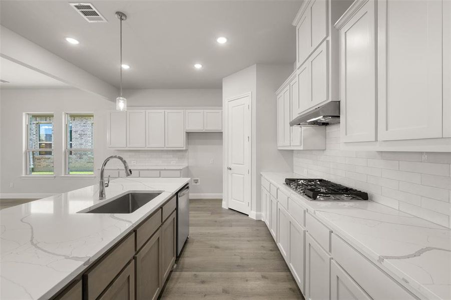 Kitchen featuring appliances with stainless steel finishes, under cabinet range hood, recessed lighting, white cabinetry, and tasteful backsplash Kitchen featuring appliances with stainless steel finishes, under cabinet range hood, recessed lighting, white cabinetry, and tasteful backsplash