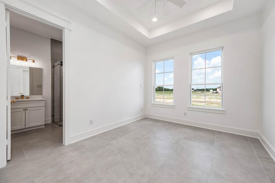 Spacious bedroom with plenty of natural light, a raised ceiling, and its own bathroom.