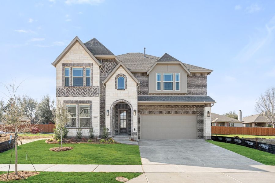 Two-story home with brick and stone exterior, arched entry, two-car garage, and green front lawn Two-story home with brick and stone exterior, arched entry, two-car garage, and green front lawn