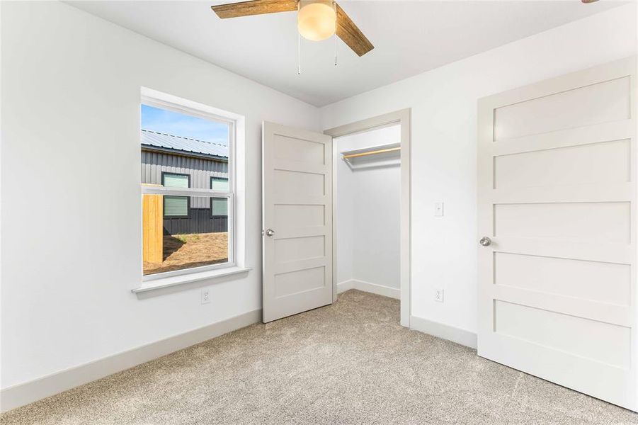 Unfurnished bedroom with light carpet, baseboards, ceiling fan, and a closet Unfurnished bedroom with light carpet, baseboards, ceiling fan, and a closet