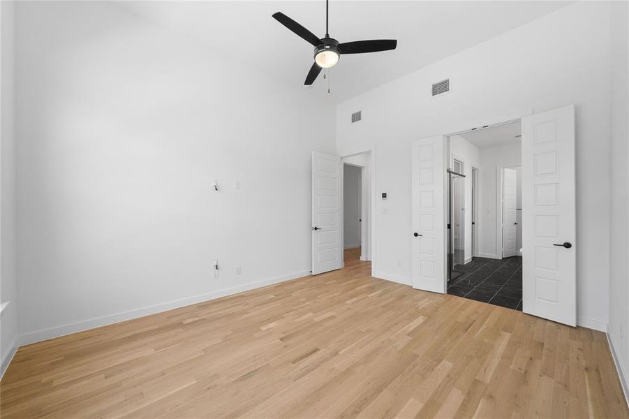 Spacious room featuring vaulted ceilings, wood-finish flooring, a contemporary ceiling fan, and white five-panel doors
