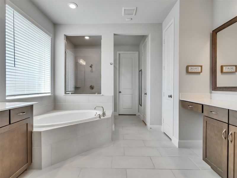 Primary bathroom has soaking tub and separate shower with closet in the rear