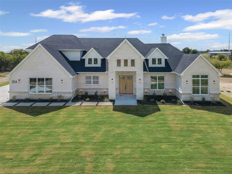 Modern farmhouse style home featuring a shingled roof, a front lawn, a chimney, stone siding, and brick siding Modern farmhouse style home featuring a shingled roof, a front lawn, a chimney, stone siding, and brick siding