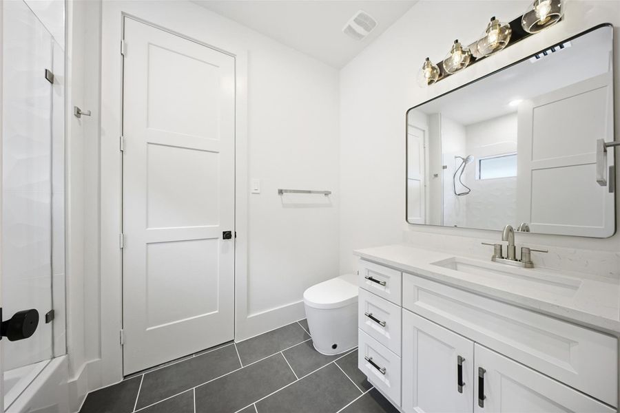 The secondary bathroom includes a modern floating-style vanity, custom tile flooring, and integrated designer lighting.