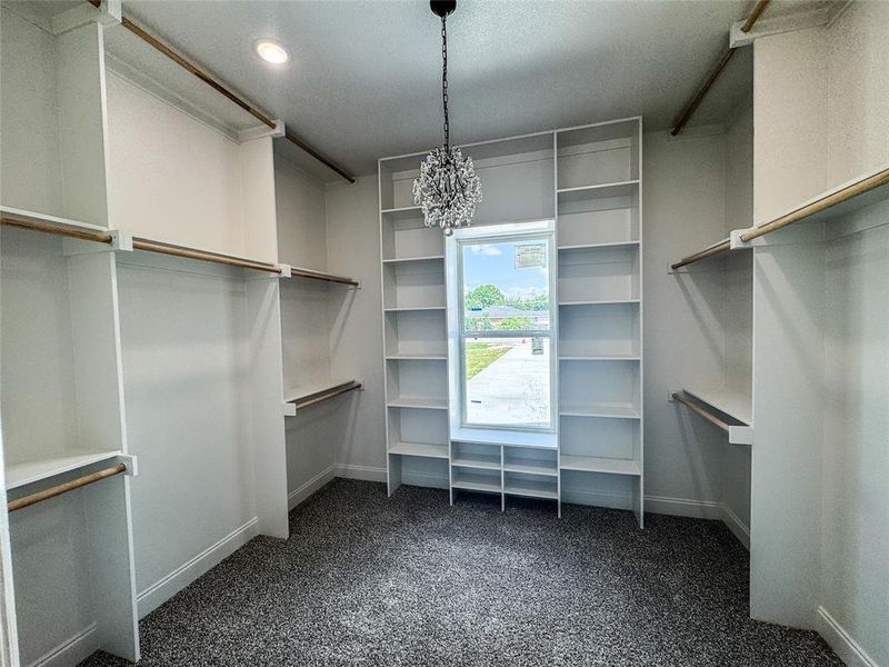 Walk in closet featuring carpet flooring and a chandelier Walk in closet featuring carpet flooring and a chandelier