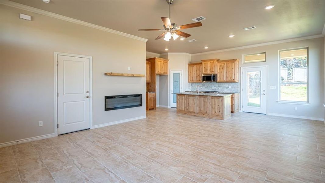 Kitchen featuring open floor plan, ceiling fan, ornamental molding, recessed lighting, and a kitchen island with sink