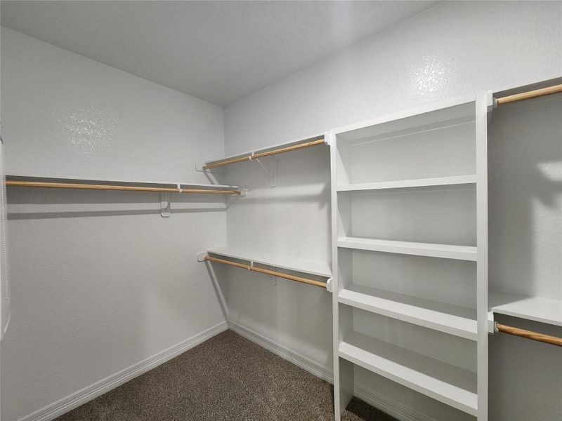 Functional custom shelving and hanging rods organize this convenient walk-in closet. Functional custom shelving and hanging rods organize this convenient walk-in closet.