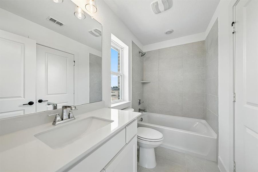 Bathroom with vanity, washtub / shower combination, and light tile patterned floors