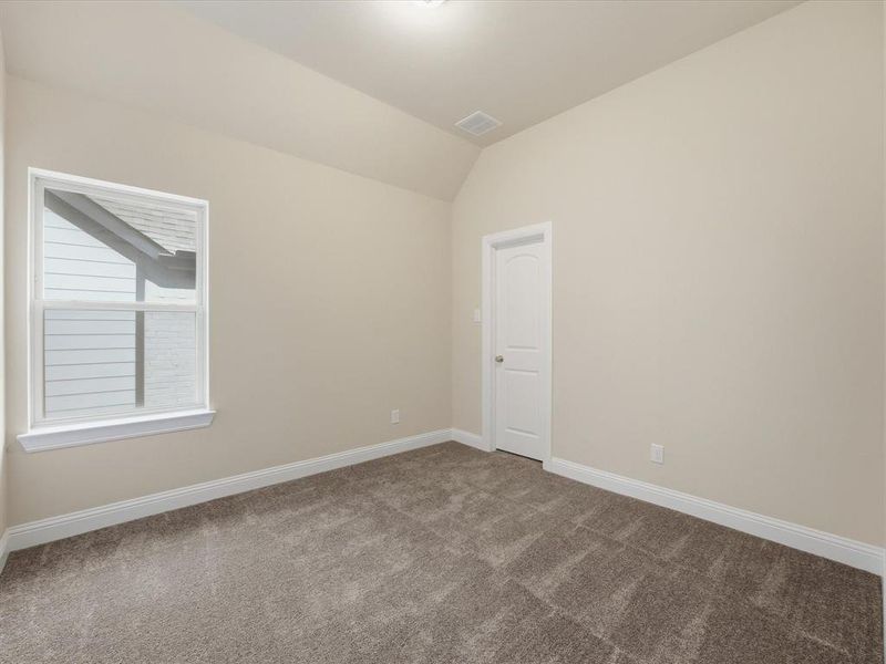 Spacious room featuring vaulted ceilings, neutral-toned walls, and plush carpeting