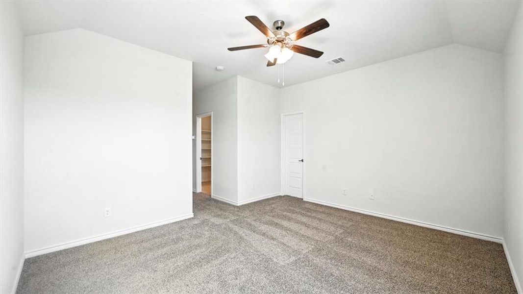 Carpeted empty room with lofted ceiling and ceiling fan