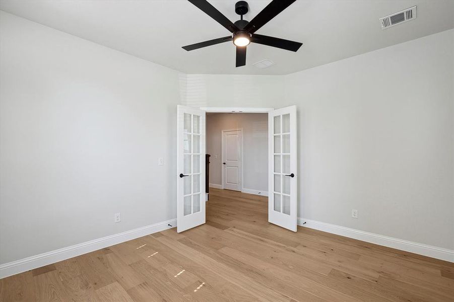 Spare room with french doors, a ceiling fan, baseboards, and light wood-style flooring