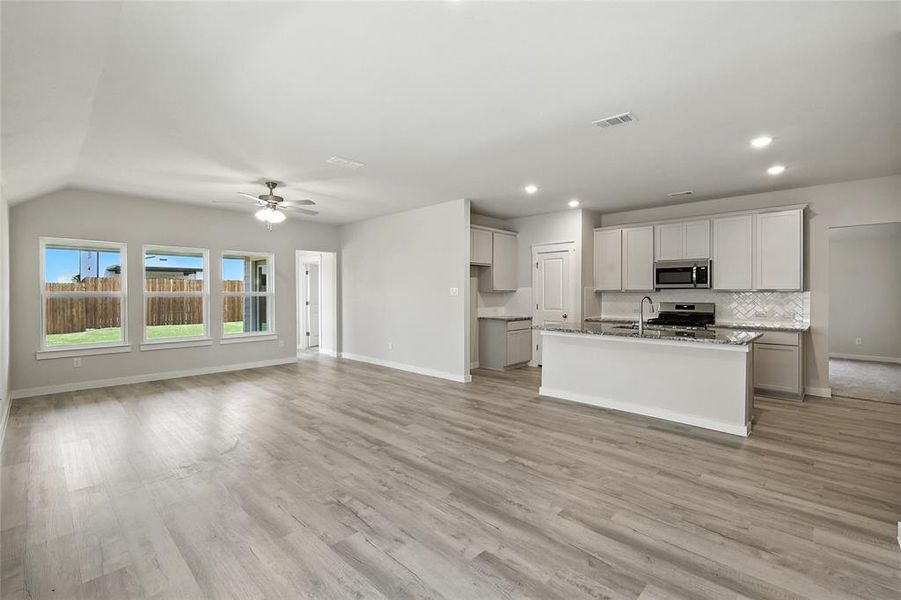 Kitchen featuring ceiling fan, a center island with sink, appliances with stainless steel finishes, decorative backsplash, and recessed lighting