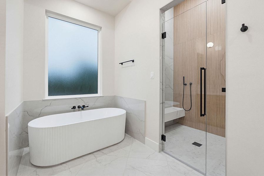 Freestanding fluted soaking tub with wall-mounted black fixtures, walk-in glass shower enclosure with built-in bench, wood-finish accent wall, and marble-look tile flooring