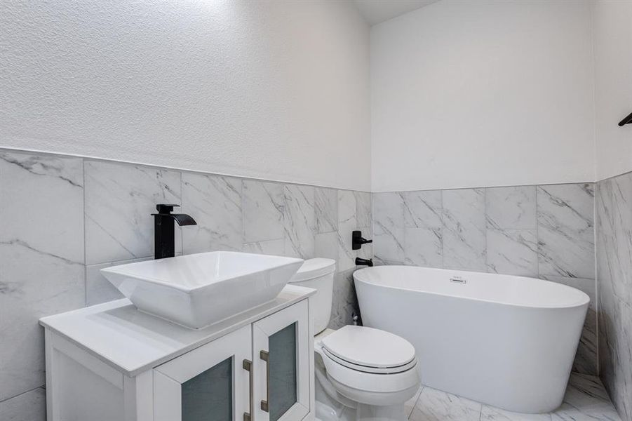 Bathroom with tile patterned flooring, tile walls, and vanity