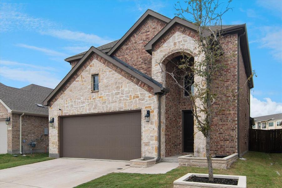 French country inspired facade featuring brick siding, driveway, and stone siding French country inspired facade featuring brick siding, driveway, and stone siding