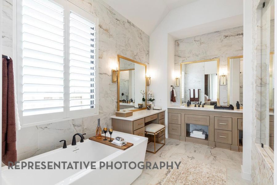 Full bathroom with a freestanding tub, lofted ceiling, marble finish floor, and vanity