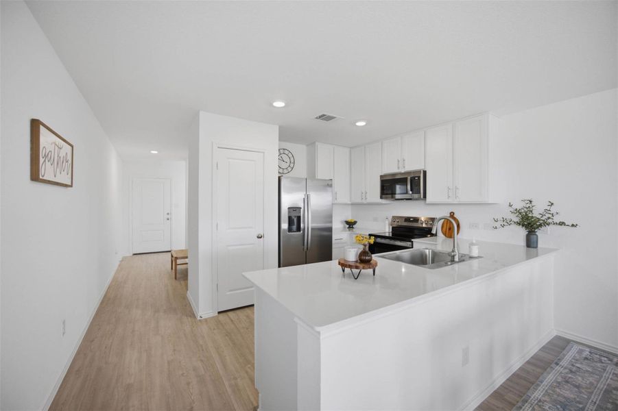 An open kitchen transitions seamlessly into the entry hallway with light flooring.