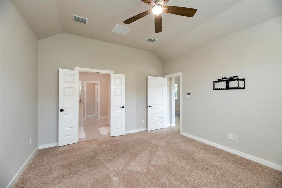 Unfurnished bedroom featuring vaulted ceiling, light colored carpet, and ceiling fan Unfurnished bedroom featuring vaulted ceiling, light colored carpet, and ceiling fan