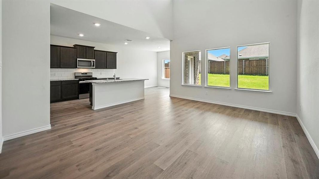 Kitchen with a center island with sink, stainless steel appliances, open floor plan, a high ceiling, and decorative backsplash