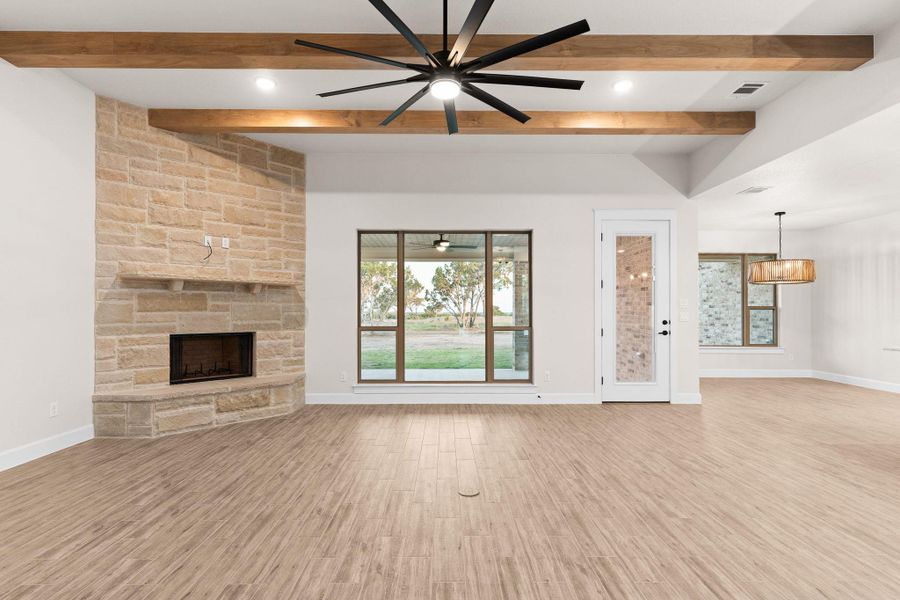 Unfurnished living room with light wood finished floors, a fireplace, beam ceiling, and ceiling fan Unfurnished living room with light wood finished floors, a fireplace, beam ceiling, and ceiling fan