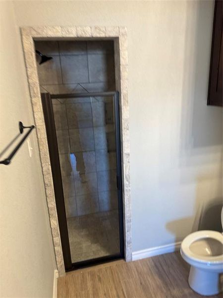 Bathroom featuring hardwood / wood-style floors, toilet, and an enclosed shower