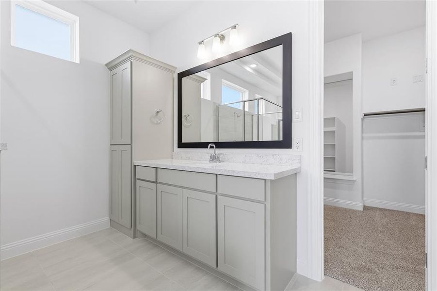 Bathroom featuring vanity, a walk in closet, a shower stall, and light colored carpet Bathroom featuring vanity, a walk in closet, a shower stall, and light colored carpet