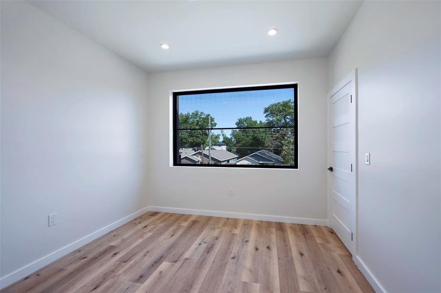 Bedroom with light hardwood / wood-style floors and walk in closet with custom oversized windows