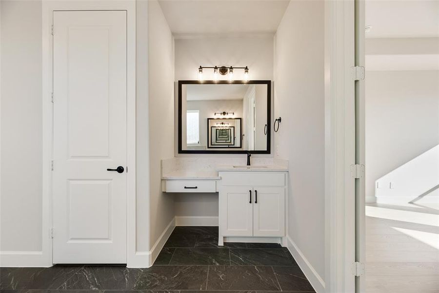 Bathroom featuring vanity and dark marble finish flooring Bathroom featuring vanity and dark marble finish flooring