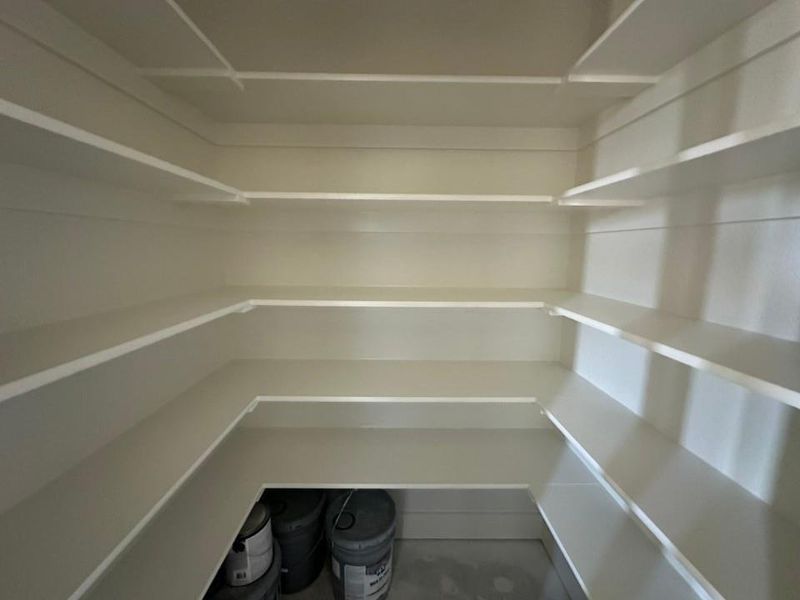 Expansive pantry featuring multi-level shelving, bright white shelving, and a light neutral wall color