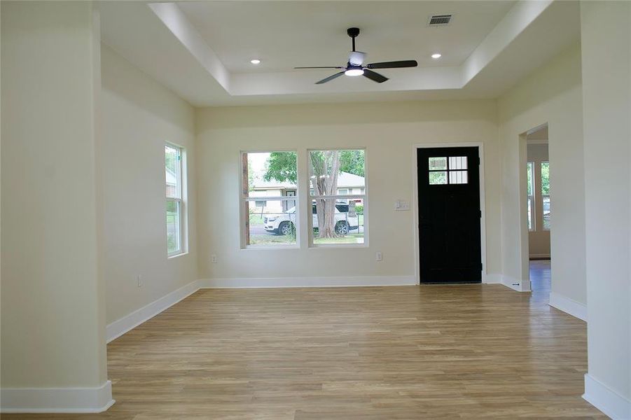 Foyer featuring light wood finished floors, a raised ceiling, recessed lighting, and ceiling fan
