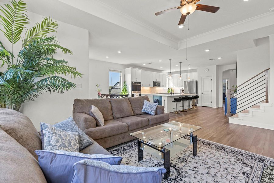 Living area featuring wood finished floors, crown molding, a ceiling fan, recessed lighting, and arched walkways