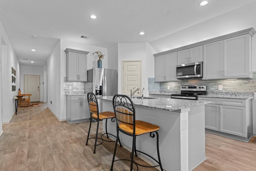 View from the kitchen toward the hallway reveals the home’s open-concept design with seamless sightlines, beautiful flooring, and abundant natural light streaming in from the back windows. View from the kitchen toward the hallway reveals the home’s open-concept design with seamless sightlines, beautiful flooring, and abundant natural light streaming in from the back windows.