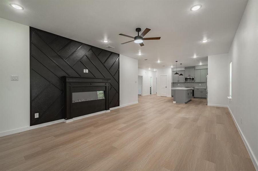 Unfurnished living room featuring ceiling fan, a fireplace, light wood finished floors, and recessed lighting Unfurnished living room featuring ceiling fan, a fireplace, light wood finished floors, and recessed lighting