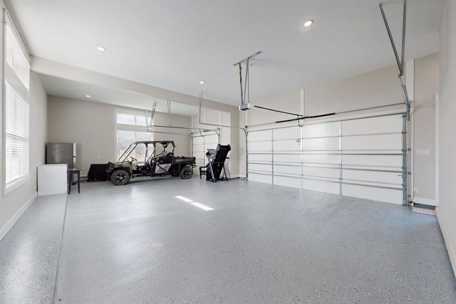 This 3 car side entry garage with lots of light has a grey blue fleck flooring surface and a big storage closet under the stairs that leads to the bonus room. Tons of driveway...Plenty for an RV and large gatherings.  Includes key pad entry and garage door openers. To the right of this garage door are the stairs to the bonus room