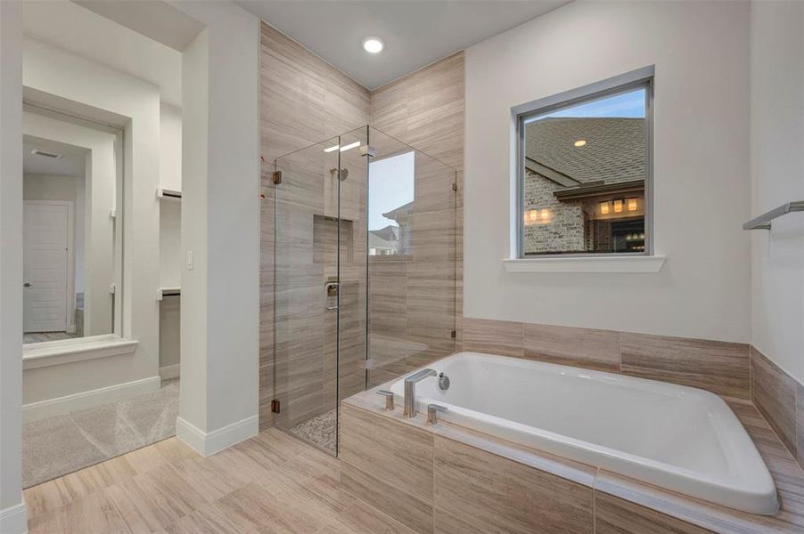 Bathroom with a bath, a stall shower, and a walk in closet