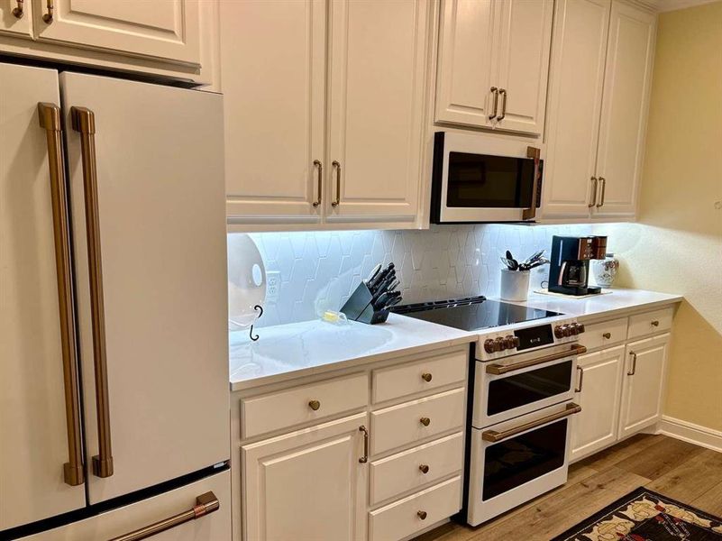 Kitchen featuring white cabinets, white appliances, and light hardwood / wood-style flooring