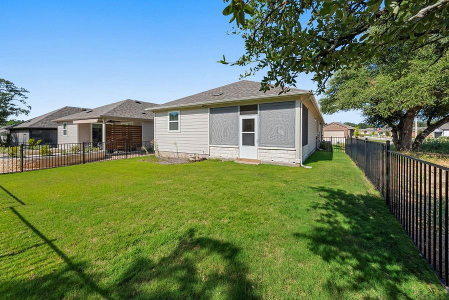 A well-kept backyard with a screened porch and black iron fencing provides a comfortable outdoor living space. A well-kept backyard with a screened porch and black iron fencing provides a comfortable outdoor living space.