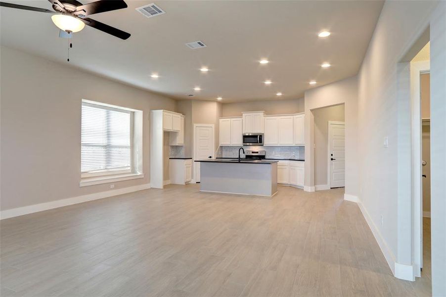 Kitchen with sink, white cabinetry, stainless steel appliances, tasteful backsplash, and an island with sink